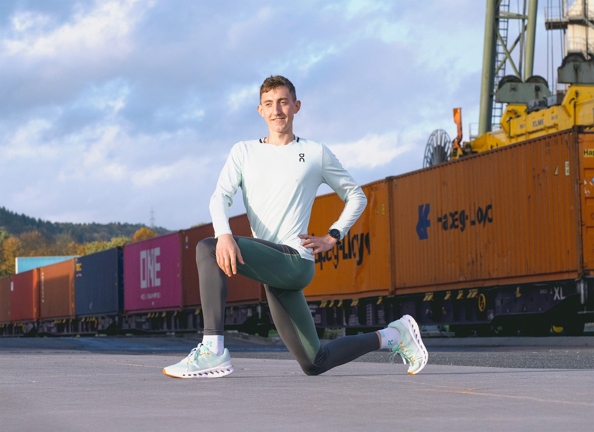 Benjamin Dern (U-23 Meister auf 5.000 Meter) macht Dehnübungen am Hafen Trier zwischen Containern und Güterzug